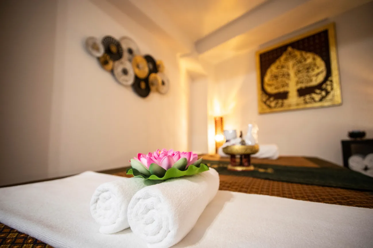 Massageliege mit Tüchern und Lotusblüte